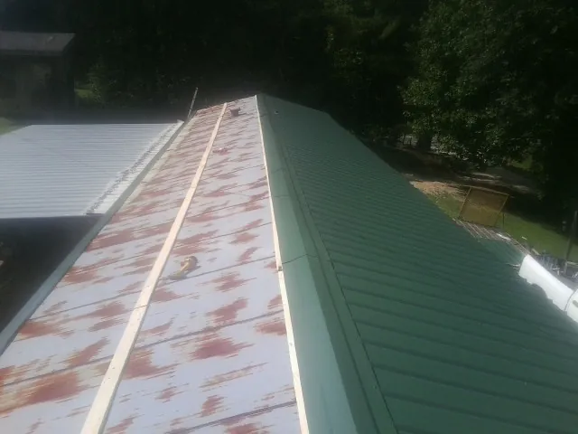 Old rusted panels beside newly installed green metal roofing — Wind Damage Roof Repair by Roofing Brothers in Eustis