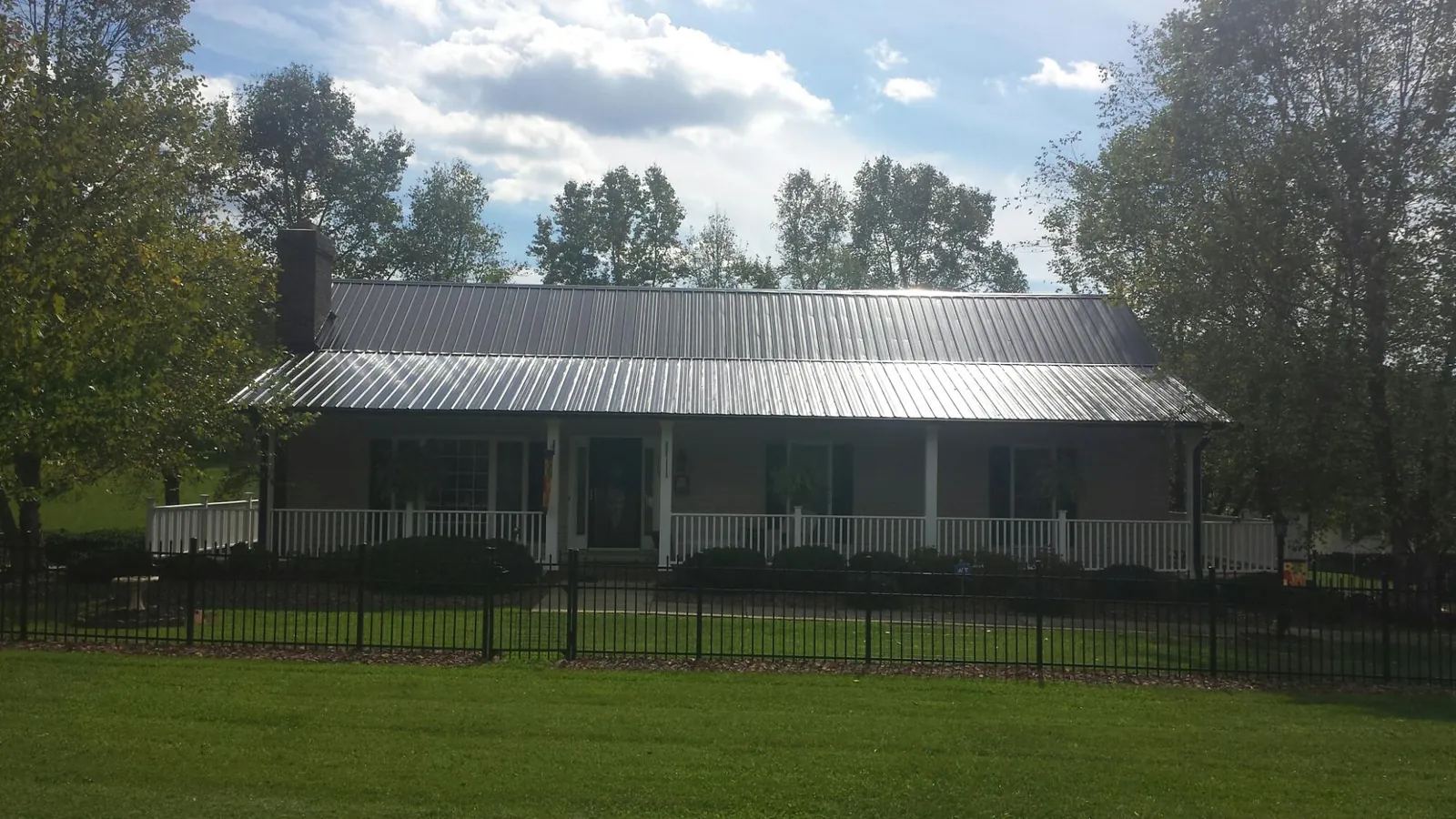 Gray metal roof on a brick ranch with a full width front porch — Gutter Guard Installation work by our crew in Eustis