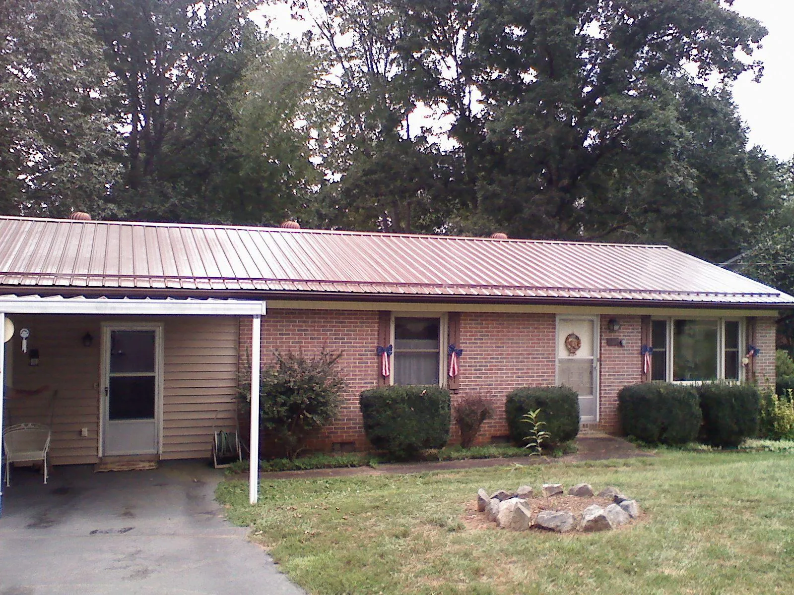 Bronze metal roof and carport on a brick ranch home — Roof Repair work by our crew in Eustis